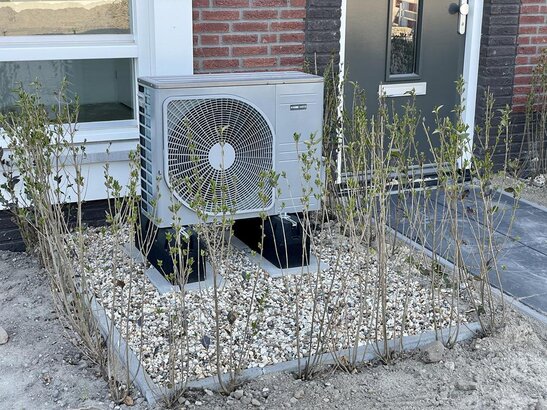 Techniker inspiziert eine Außen-Wärmepumpe an einem Einfamilienhaus